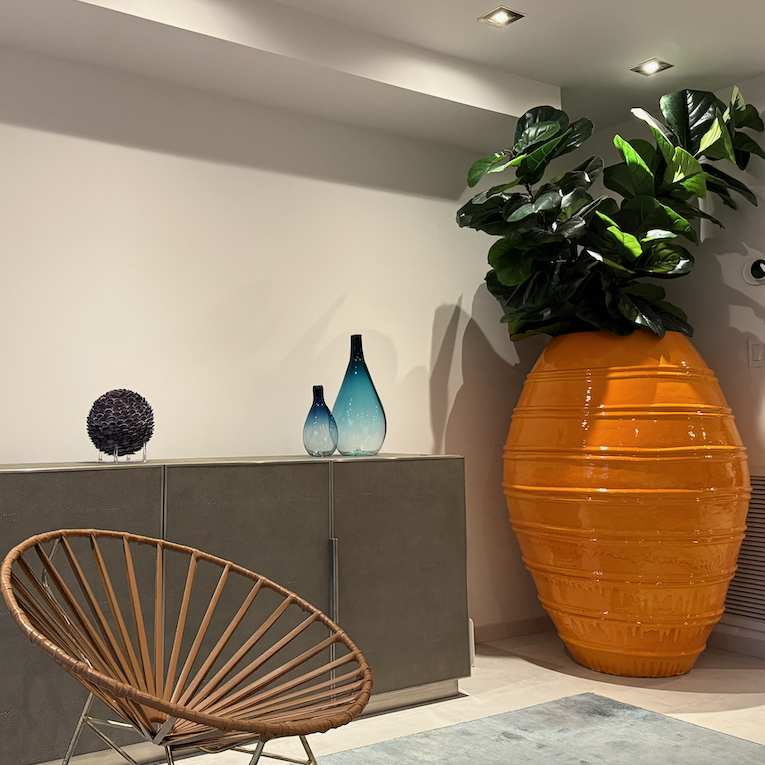 Wooden shelf with gray and olive drab green baseball caps, next to wooden clothes hanger with sweaters.